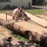 person using chainsaw mill on log