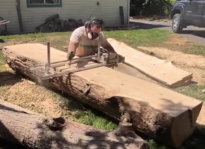 person using chainsaw mill on log